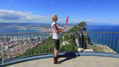 Woman enjoying with the British flag in hand on top of Gibraltar Rock. Gibraltar is a territory of South West Europe Which is part of the United Kingdom.