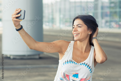 Smiling woman taking a selfie photo in an urban street Free Download Smiling woman taking a selfie photo in an urban street - GFXLoad