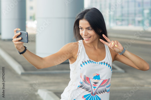 Smiling woman taking a selfie photo in an urban street Free Download Smiling woman taking a selfie photo in an urban street - GFXLoad