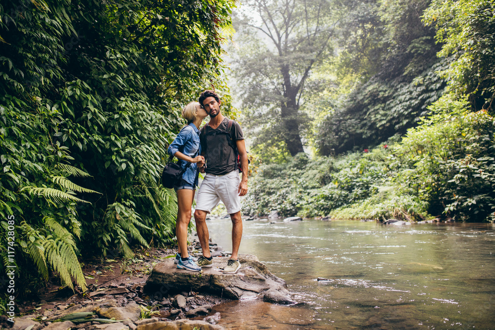 Loving couple standing by mountain stream Loving couple standing by mountain stream