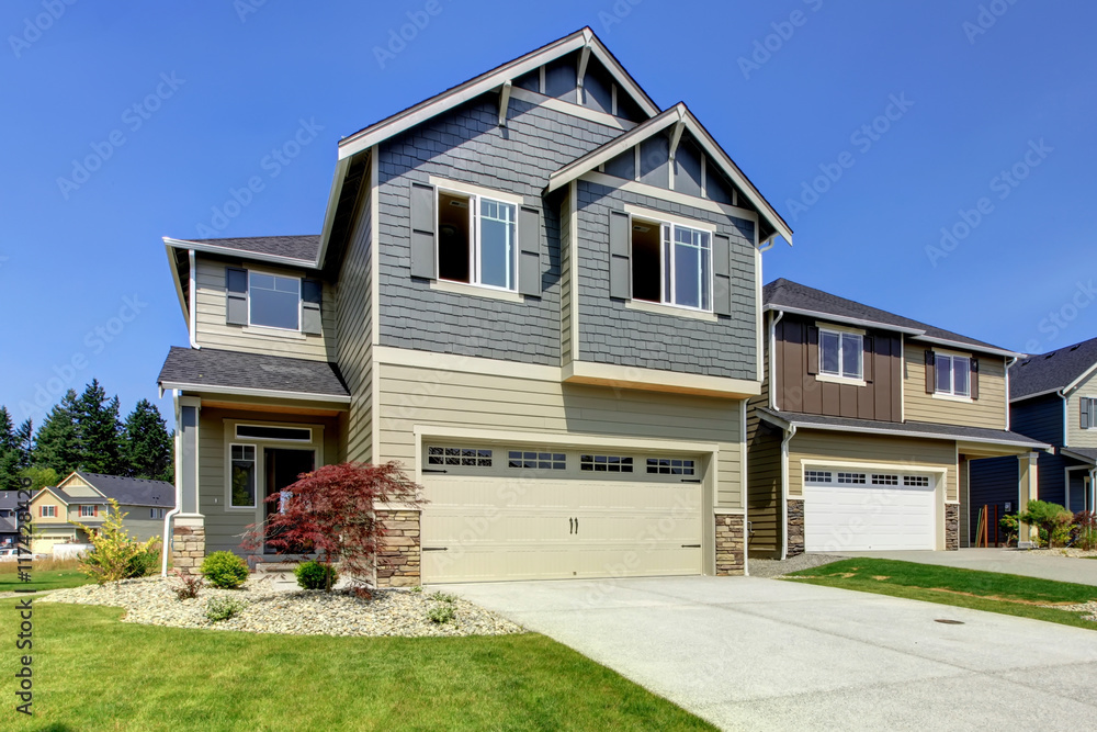 Beautiful grey house exterior with stone, green lawn and driveway. Beautiful grey house exterior with stone, green lawn and driveway.
