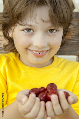 Full palm ripe cherries in hands of the boy