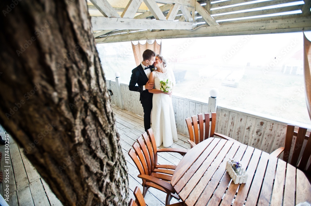 Wedding couple hugging at wooden  cafe
