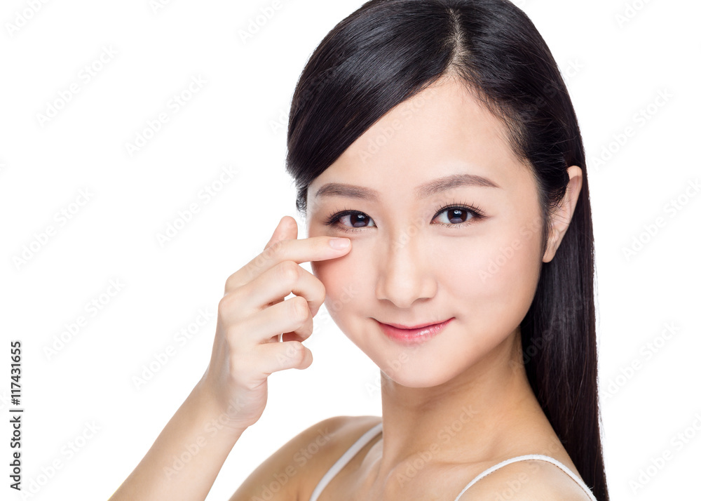 Smiling beautiful young woman face with finegr touch on her eye Smiling beautiful young woman face with finegr touch on her eye