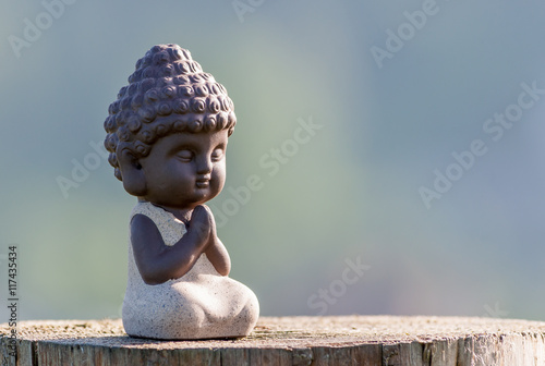 silhouette of little buddha or baby practicing yoga, meditate and pray on wooden surface