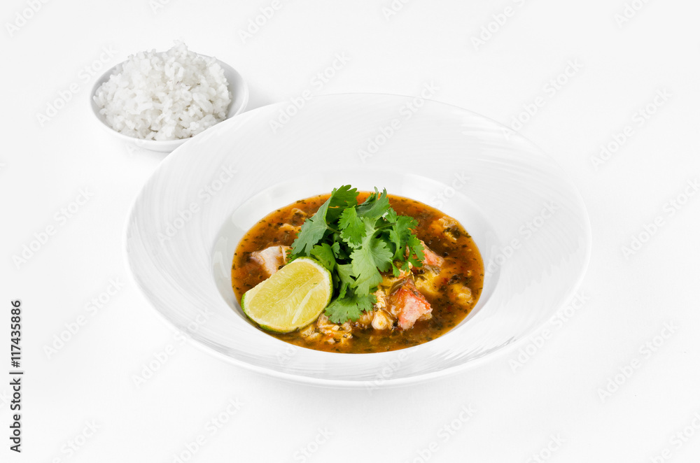 Crab with chili sauce, lime, parsley and rice on a plate on a white background