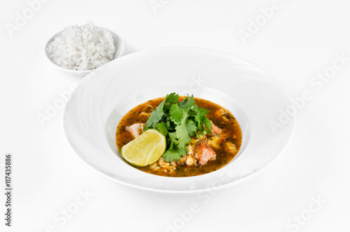 Crab with chili sauce, lime, parsley and rice on a plate on a white background