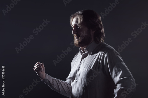 Man threatens with fist, profile on dark background, the silhouette.