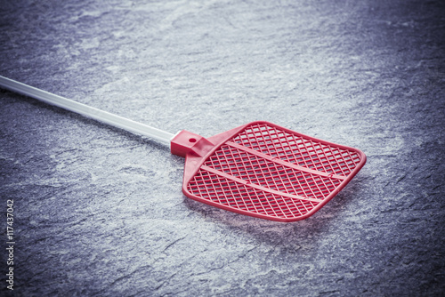 Fly swatter on stone table. Concept of exterminating bugs and insects. photo