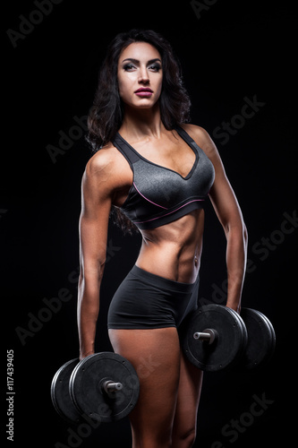 studio shot of perfect body of bodybuilder female with dumbbells