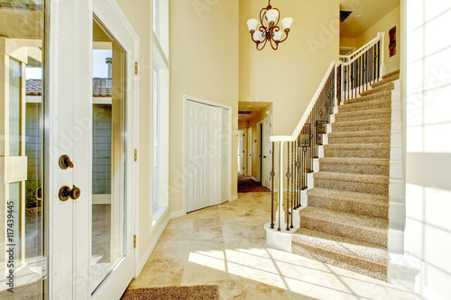Bright creamy tones entryway with staircase and tile flooring.