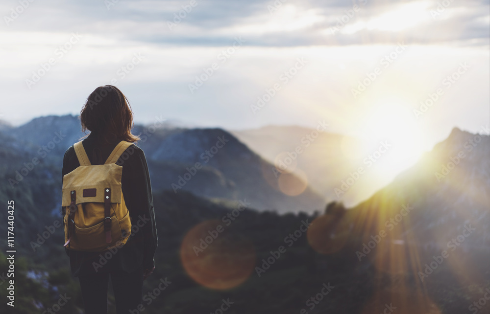 Fototapeta premium Hipster młoda dziewczyna z plecakiem, podziwiając zachód słońca na szczycie mglistej góry. Turystyczny podróżnik na makiecie widoku tła. Turysta patrząc na rozbłysk słońca w podróży do Hiszpanii. Picos de Europa. Koncepcja podróży