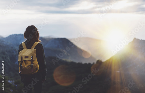 Valokuvatapetti Hipster young girl with backpack enjoying sunset on peak of foggy mountain