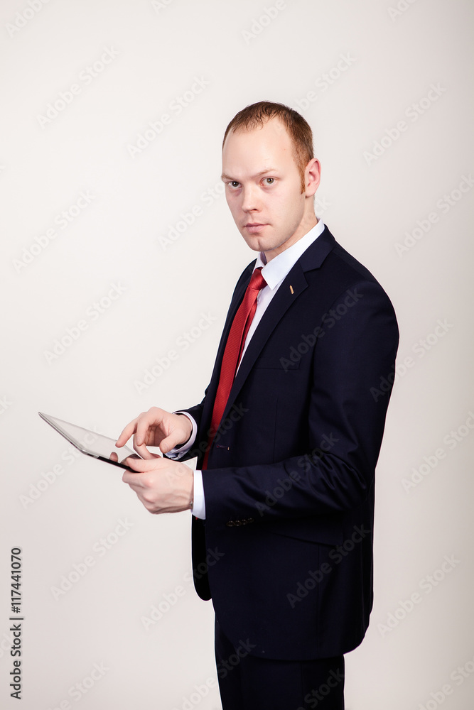 Creative young programmer in a business suit with a tie and sunglasses presents with a smile on his face display a tablet. Creative young programmer in a business suit with a tie and sunglasses presents with a smile on his face display a tablet.