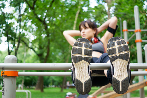 Athletic woman doing exercises on bars, sneakers closeup