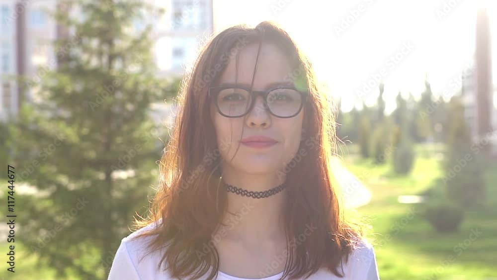 Video portrait teenage girl wearing glasses walking in the park look at camera HD