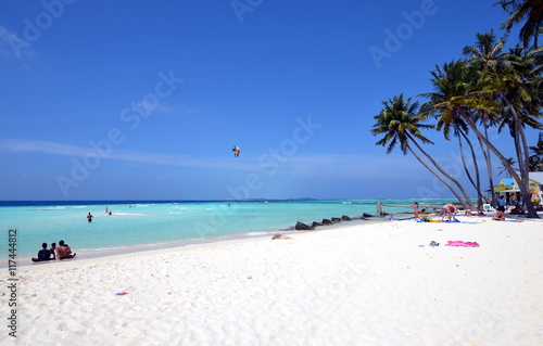 Fototapeta Naklejka Na Ścianę i Meble -  Maldivian white sand beach with palm trees, azure water and windsurfing
