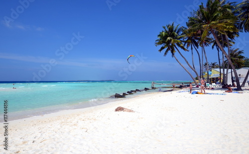 Fototapeta Naklejka Na Ścianę i Meble -  Maldivian white sand beach with palm trees, azure water and windsurfing