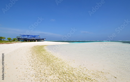 Maldivian beach with white sand, azure water and old blue boat