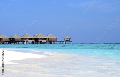Maldivian beach with white sand, azure water and wooden villas