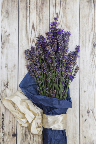 Lavender wrapped in paper with silk ribbon on wooden background