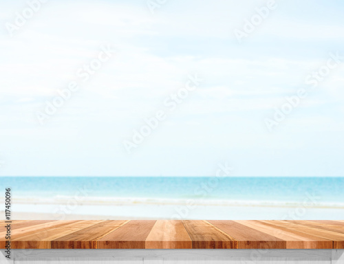 Wood plank table top with blurred sea and blue sky at background