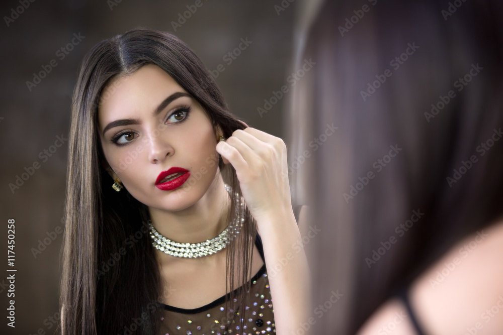 Young beautiful brunette looks in the mirror. Young beautiful brunette looks in the mirror.