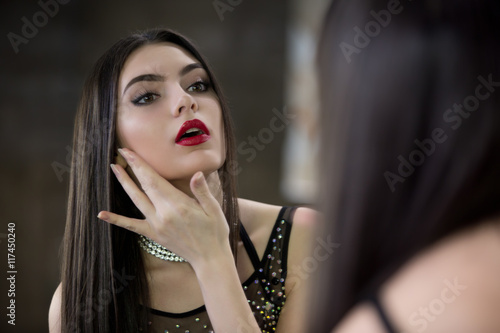Fotografía Young beautiful brunette looks in the mirror.
