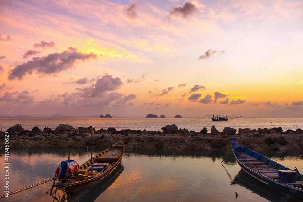 Sunset, boats and stones in the sea on a tropical island