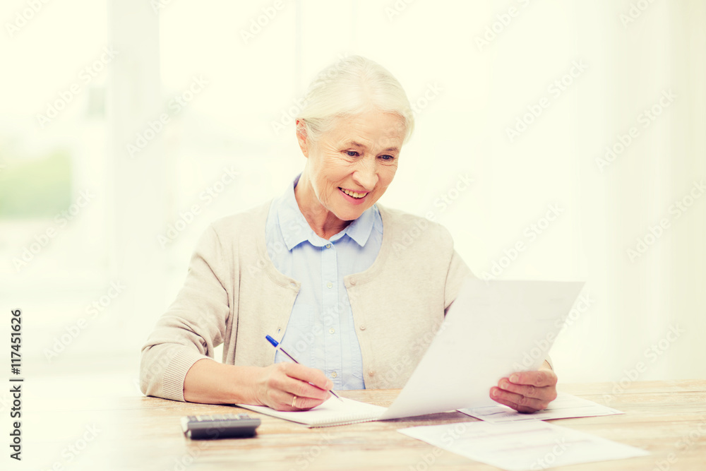 senior woman with papers and calculator at home senior woman with papers and calculator at home