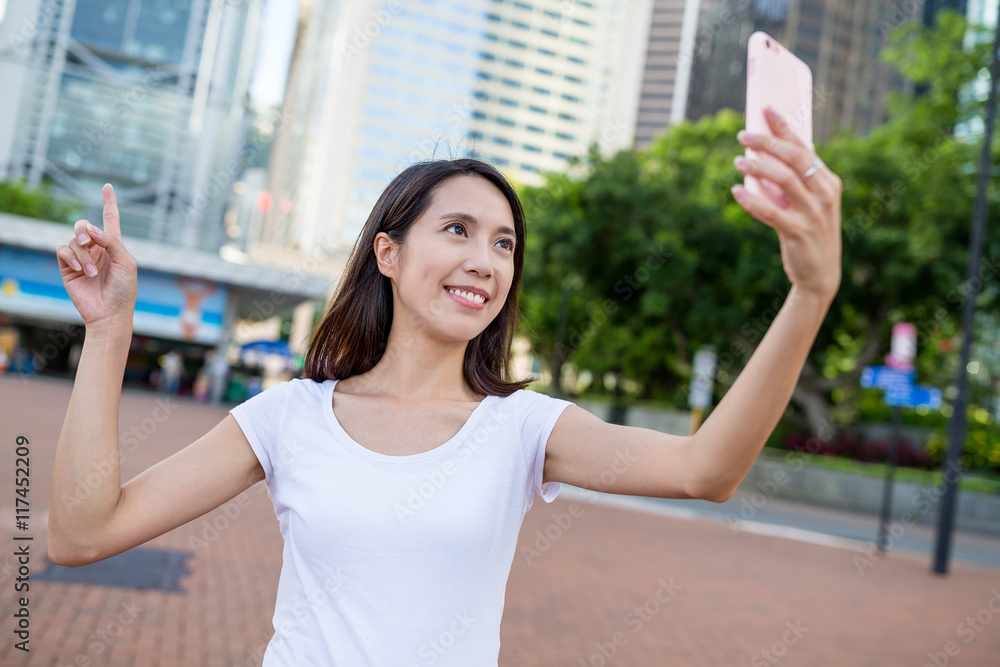 Woman taking photo by mobile phone in Hong Kong city