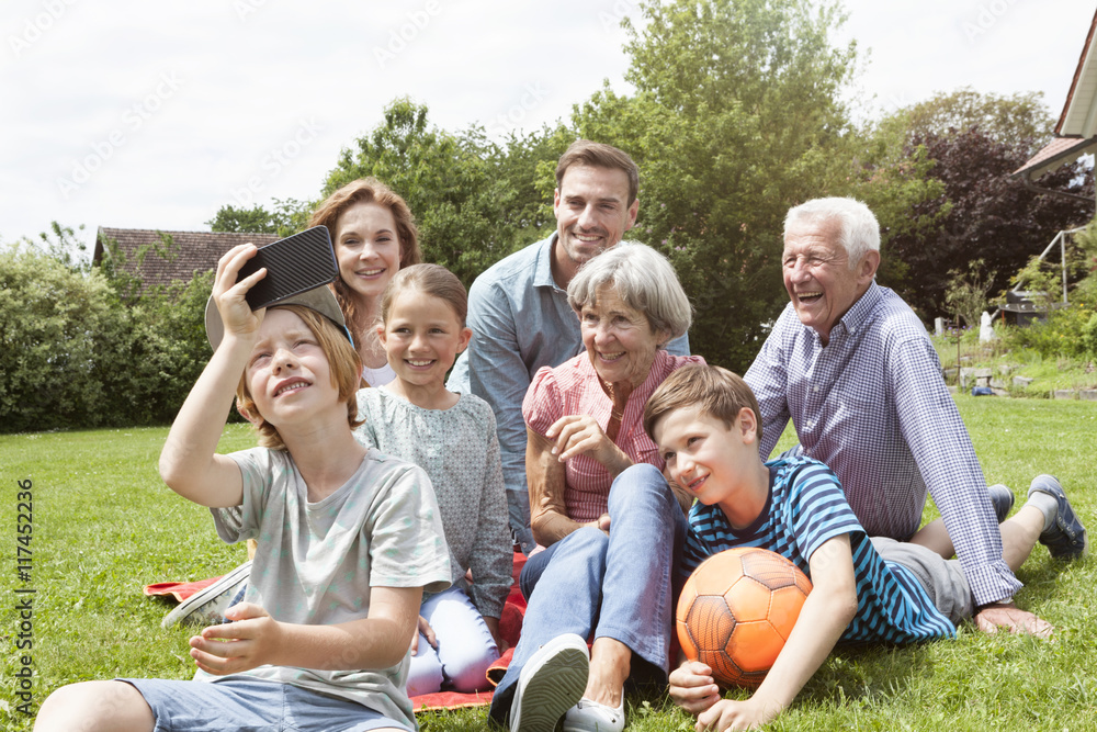 Boy taking selfie of happy extended family in garden Boy taking selfie of happy extended family in garden
