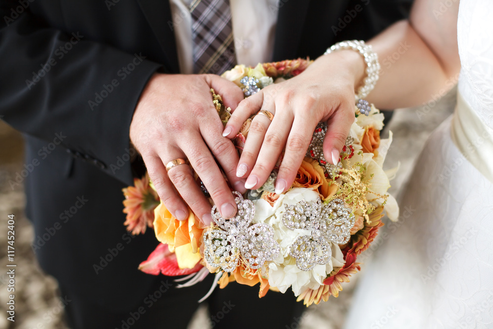 Hands of bride and groom on wedding bouquet. Marriage concept Hands of bride and groom on wedding bouquet. Marriage concept