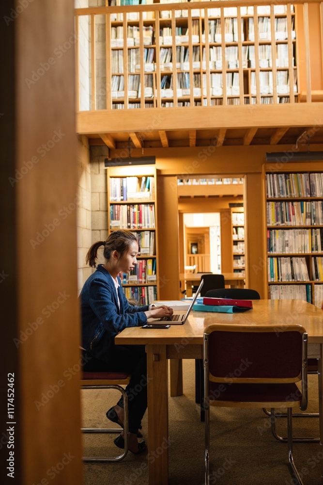 Young woman using laptop in library Young woman using laptop in library