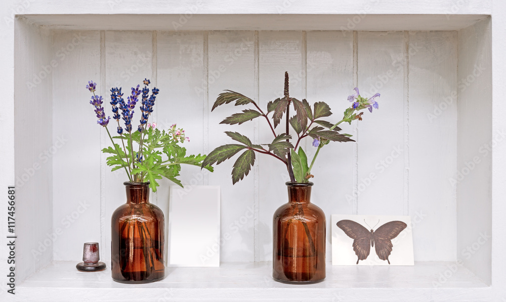 Fototapeta premium Shelf with lavender and geranium in old pharmacy bottles.