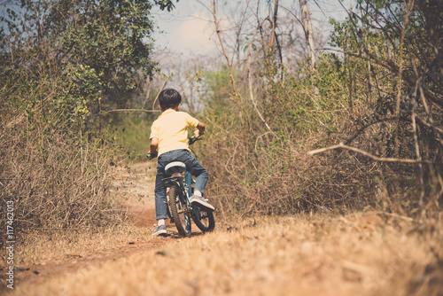 Little boy ride bicycle on the rock road.