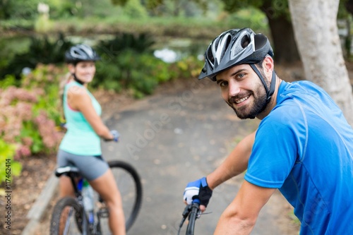 Athletic couple standing with mountain bike in forest