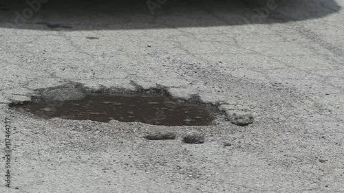 Tire Hits Pothole Puddle Slow Motion. a close up of a pothole filled with water. Truck tires hit it in slow motion splashing water everywhere
