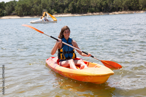 Fit woman rowing on lake in a kayak and smiling