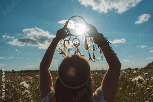 girl with a dream catcher in the hands of the sun