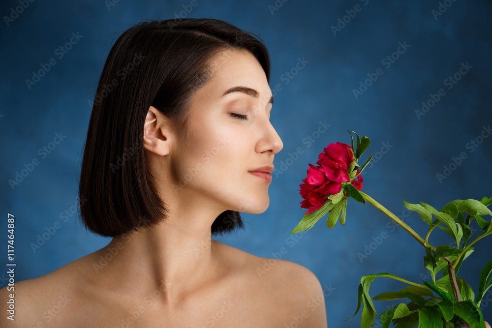 Close up portrait of tender young girl with red flowers over blue background