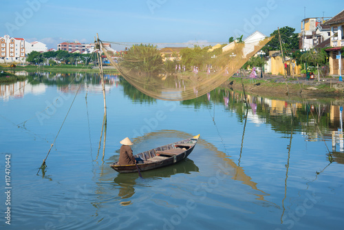 The fisherman on the boat with fishing net on the Thu Bon river in the early morning. Hoi An, Vietnam photo