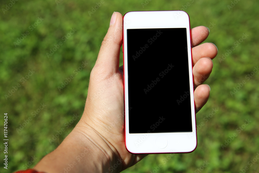 Hand holding smartphone against green background Hand holding smartphone against green background