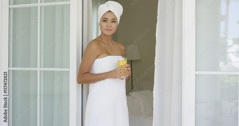 Gorgeous woman wrapped in towel outside with glass of orange juice while leaning against door Gorgeous woman wrapped in towel outside with glass of orange juice while leaning against door