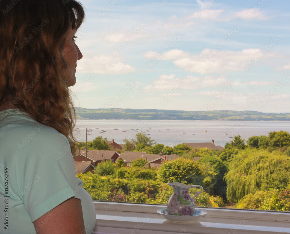 A Woman Admires an Ocean View Through a Window