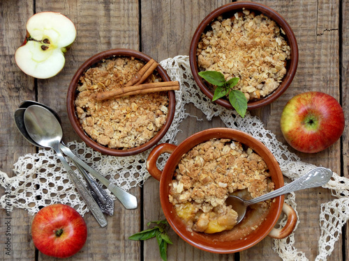 Cheese casserole or crumble with apples and cinnamon in brown cup ramekin on wooden background