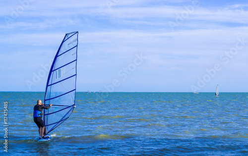 Lone windsurfer back-first in the sea catching a wave