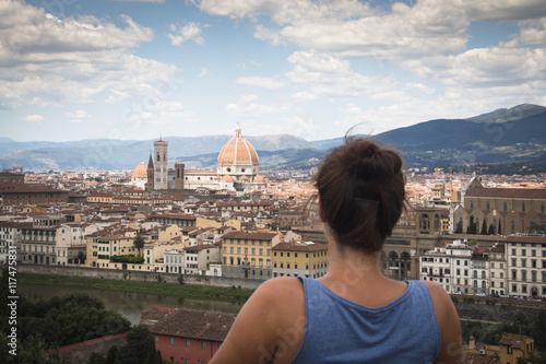 Girl looking over the historical center of Florence in Italy. The photo is taken from piazzale Michelangelo and shows the Arno river, the Duomo and many other churches and buildings 