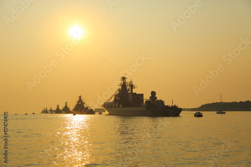 silhouettes of warships at sunset