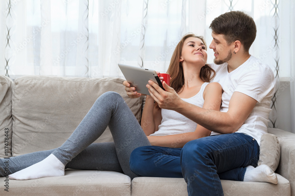 Man and young woman sitting on a couch and using tablet. Man and young woman sitting on a couch and using tablet.